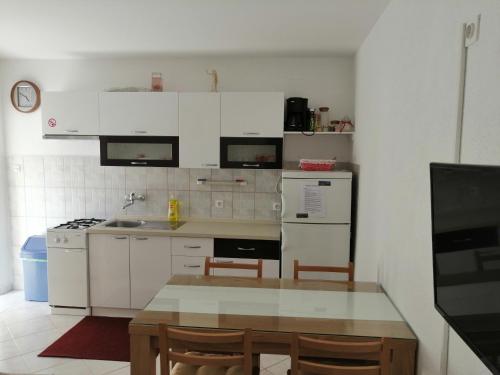eine Küche mit weißen Schränken und einem Tisch mit Stühlen in der Unterkunft Apartment with sea view terrace in Betina