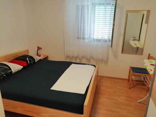 Schlafzimmer mit einem Bett, einem Spiegel und einem Fenster in der Unterkunft Apartment with sea view terrace in Betina