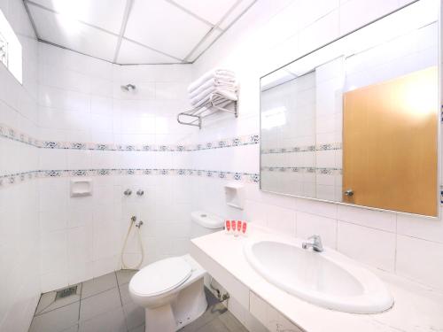 ein Badezimmer mit einem Waschbecken, einem WC und einem Spiegel in der Unterkunft Super OYO 447 Comfort Hotel Meru in Klang