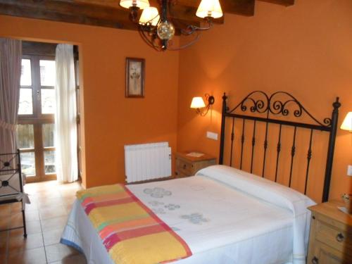 1 dormitorio con 1 cama en una habitación con paredes de color naranja en Apartamentos Rurales Los Villares, en Colunga