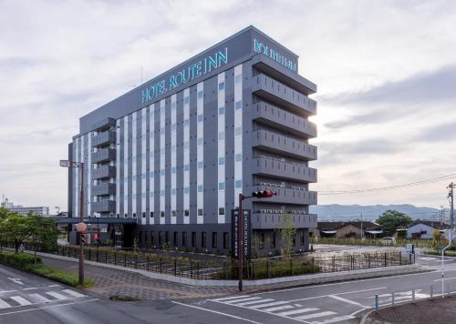a large white building with a sign on it at Hotel Route-Inn Kurashiki Mizushima in Kurashiki