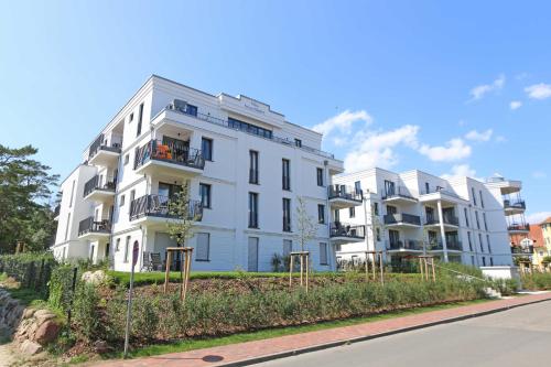 a white building on the side of a street at Villa Düne - Ferinewohnung 07 Morgensonne in Baabe