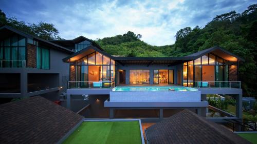 a hotel room with a pool and a house at The Senses Resort & Pool Villas - SHA Plus in Patong Beach