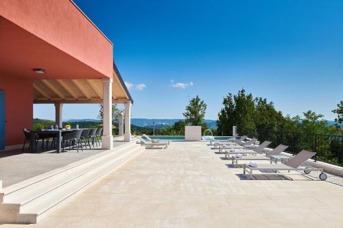 un patio con sillas, una mesa y una piscina en Rainis Hill Top Villa, en Oprtalj