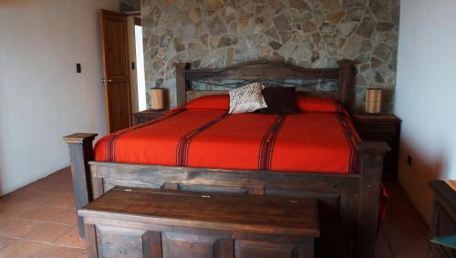 a bedroom with a wooden bed with a red comforter at Atitlan Villas in San Antonio Palopó