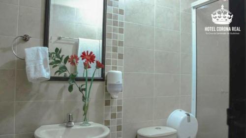 een badkamer met een toilet, een wastafel en een spiegel bij Hotel corona real in Santander de Quilichao