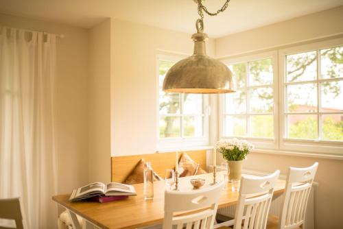 a dining room table with white chairs and a pendant light at Grüne Hufe in Born