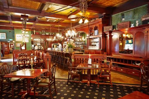 een restaurant met houten tafels en stoelen en een bar bij Parkhotel Mastbosch Breda in Breda