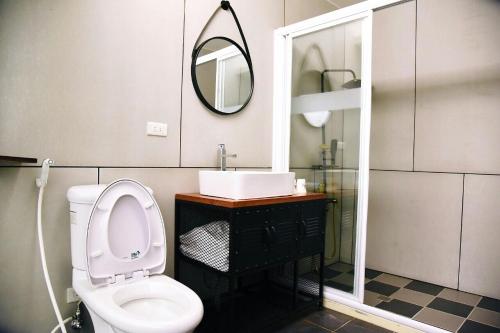 La salle de bains est pourvue de toilettes, d'un lavabo et d'un miroir. dans l'établissement Tian Fang Ye Tan Hotel, à Yilan