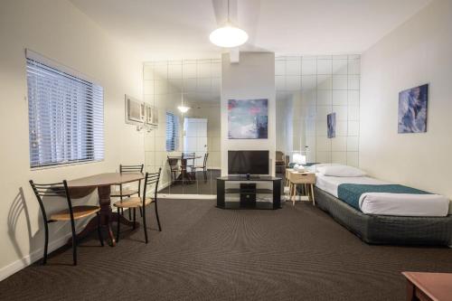 a bedroom with a bed and a table and a dining room at Greenways Apartments in Adelaide