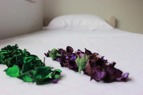 a pile of green and purple flowers on a bed at House Legacy in Bihać