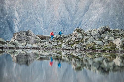 two people walking on rocks near a body of water at Sporthotel Cristall in Fulpmes