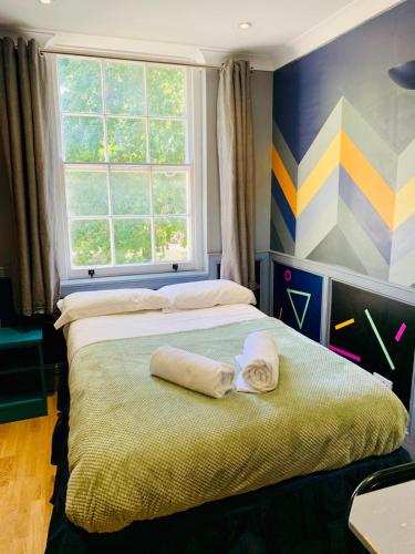 a bedroom with two towels on a bed with a window at KX Rooms Kings Cross in London