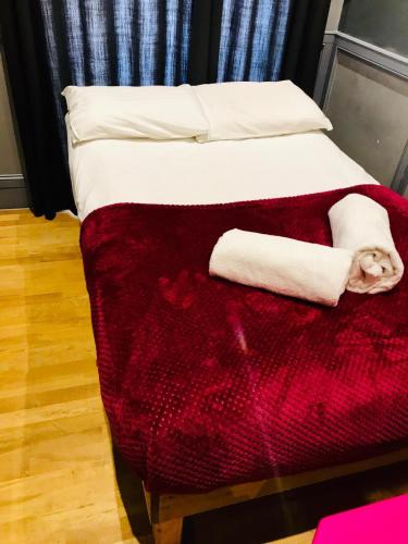 a bed with a red blanket and white pillows at KX Rooms Kings Cross in London