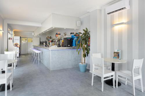 ein Restaurant mit weißen Tischen und Stühlen und einer Theke in der Unterkunft Hotel Apartamentos Vibra Central City - Adults only in Sant Antoni de Portmany