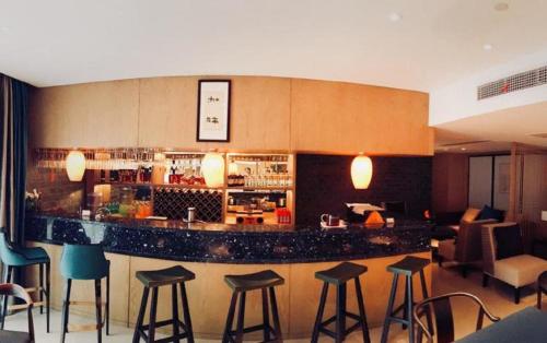 um bar num quarto de hotel com bancos em Ramada by Wyndham Zhenjiang City Center em Zhenjiang