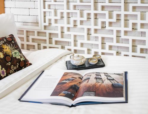 a book on a bed with a tea set on it at AMOY by Far East Hospitality in Singapore