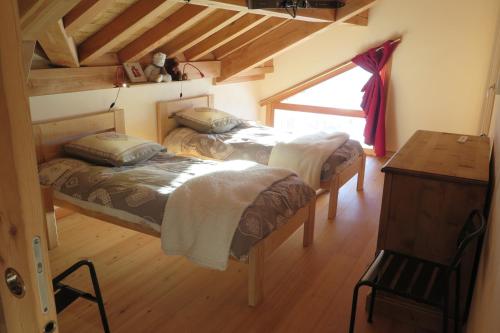 a bedroom with two beds and a table and a window at Les Chalets du Chaberton, Pied de pistes et Spa in Montgenèvre