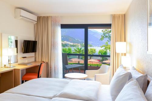 ロカルノにあるH4 ホテル アルカディア ロカルノのベッドと大きな窓が備わるホテルルームです。