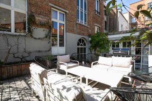 a patio with white tables and chairs in front of a building at Fish Market B&B in Brussels