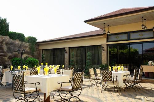 a patio with white tables and chairs with yellow wine glasses at Hotel Forum in Pazardzhik