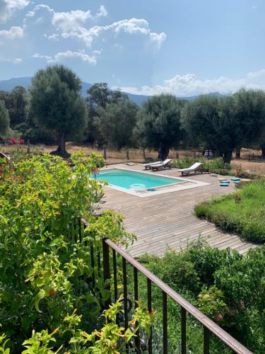 a swimming pool in a garden with a wooden deck at Domaine de Tappa - Casa Filicina in Sollacaro