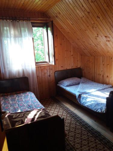 two beds in a log cabin with a window at Bosaca apartment in Žabljak