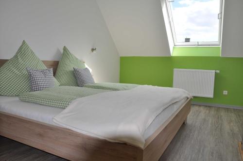 Un dormitorio con una cama con paredes verdes y una ventana en Ferienwohnung Vollert, en Willsbach