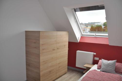 a bedroom with a wooden cabinet and a window at Ferienwohnung Vollert in Obersulm