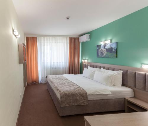 a hotel room with a bed and a blue wall at Hotel Livade in Čačak