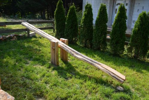 a wooden rail in the grass next to a fence at Planinska Gospa in Bajina Bašta