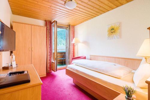 Dormitorio con cama, escritorio y TV en Bernerhof Swiss Quality Hotel, en Kandersteg