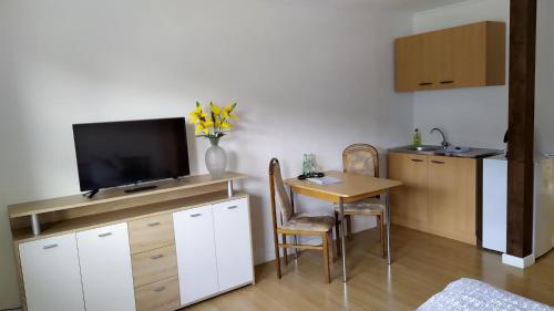 a living room with a table and a tv and a kitchen at Greizer Kammhütte Gaststätte & Pension in Klingenthal