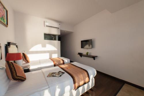 a bedroom with two beds and a tv on the wall at Bellevue Hotel in Nha Trang