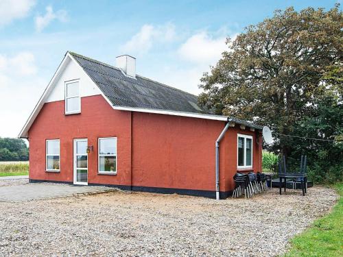 une maison rouge avec une table de pique-nique devant elle dans l'établissement 12 person holiday home in Bredebro, à Bredebro