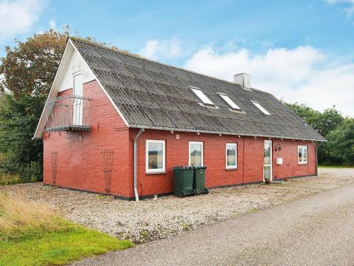 um edifício vermelho com um telhado preto numa estrada em 12 person holiday home in Bredebro em Bredebro