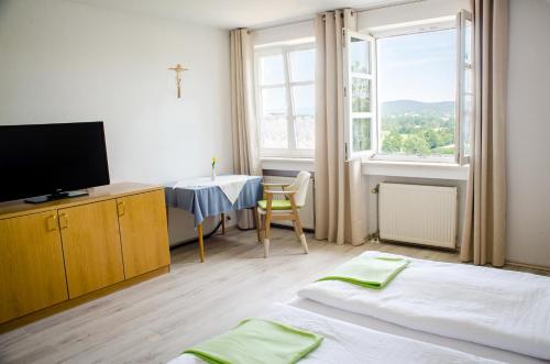um quarto com duas camas e uma televisão e uma mesa em Wallfahrts-Gaststätte Heilbrünnl em Roding