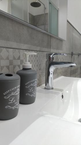 a bathroom sink with a faucet and a soap container at Sunrise Beach Apartment Trapani in Trapani