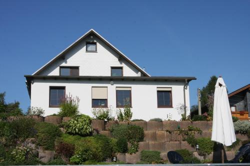 a white house with a fence and an umbrella at Ferienwohnung Hauptmann in Frauenwald