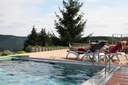a woman laying in lawn chairs next to a swimming pool at Ferienwohnung Hauptmann in Frauenwald