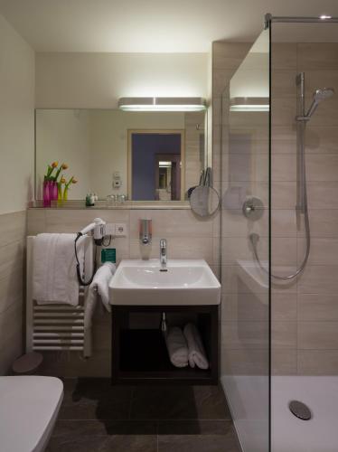 a bathroom with a sink and a shower at Garni Hotel Schumacher in Filderstadt