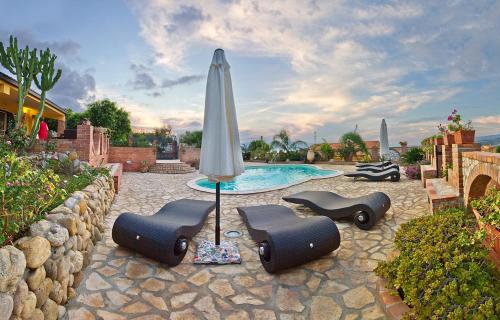 a umbrella and chairs next to a swimming pool at B&B La Collina Felice in Pellaro