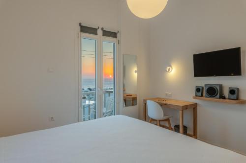 una camera da letto con un letto, una scrivania e una televisione di Gazia Sea View House - Mykonos Town a Mykonos Città