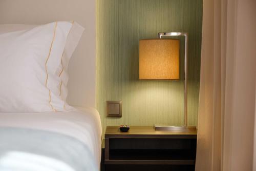 a bedroom with a bed and a table with a lamp at SDivine Fatima Hotel, Congress & Spirituality in Fátima