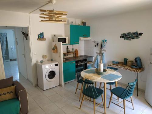 a kitchen with a table and chairs and a washing machine at Résidence Village Marin Catalan TORREILLES PLAGE in Torreilles