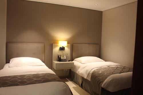 a hotel room with two beds and a lamp at Mövenpick Hotel & Resort Al Bida'a in Kuwait