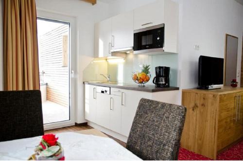 a kitchen with white cabinets and a table and chairs at Chalet Barbara in Ischgl