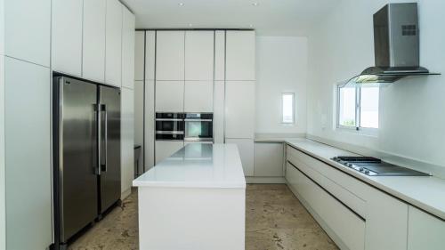 a kitchen with white counters and a refrigerator at Cap el Limon Luxury Villas in El Limón