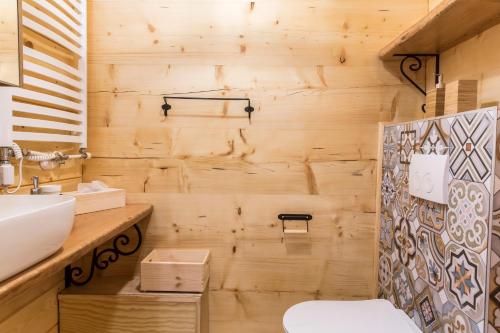 a bathroom with a wooden wall with a toilet and a sink at TatryTop Osada Luxury Chalets Kościelisko in Kościelisko