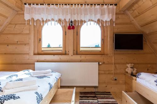a log cabin bedroom with two beds and a flat screen tv at TatryTop Osada Luxury Chalets Kościelisko in Kościelisko